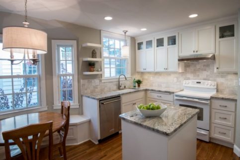 A kitchen with custom white cabinets and custom granite counter tops.